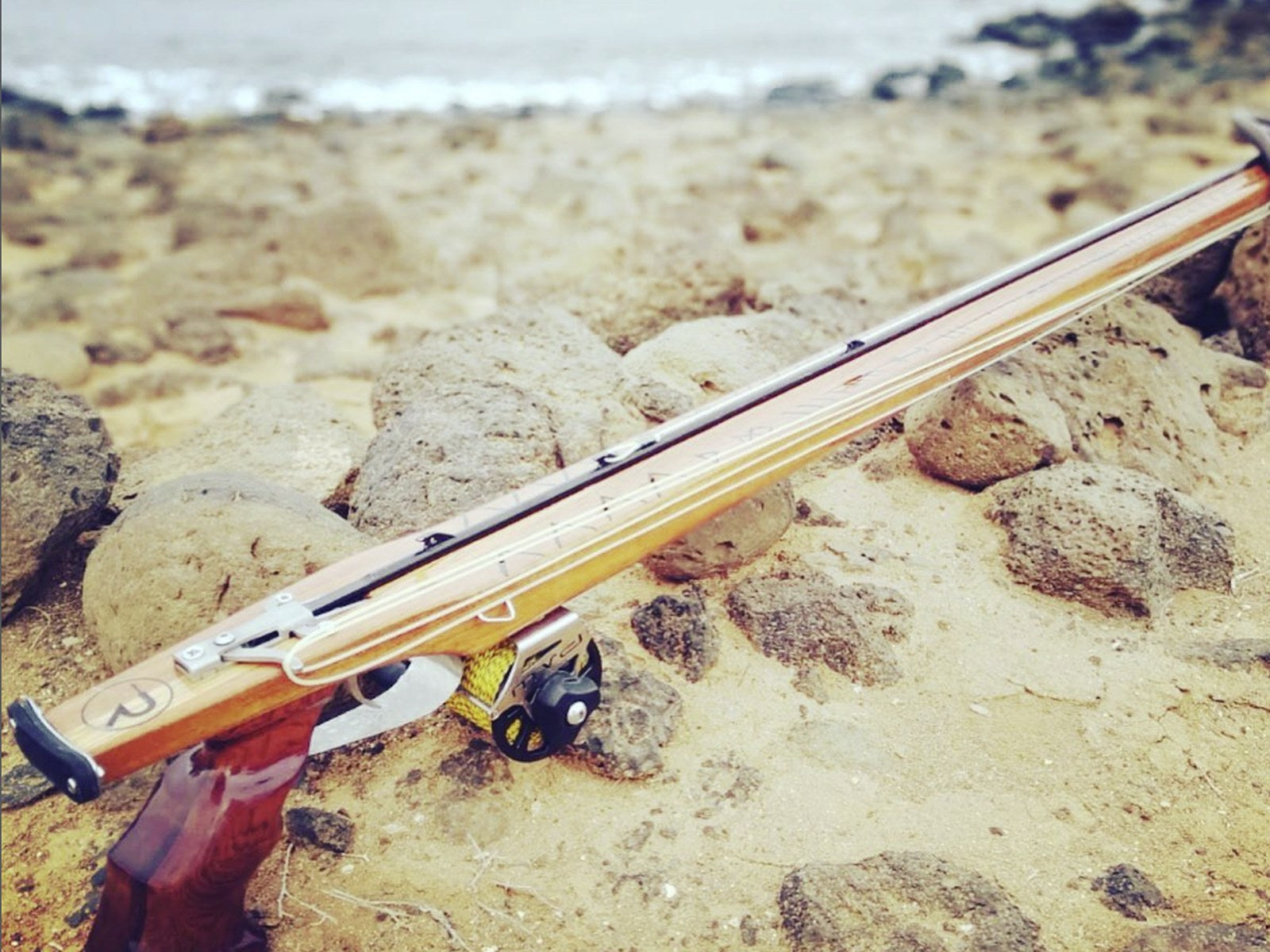 Rocco wooden speargun on the rocks by the sea